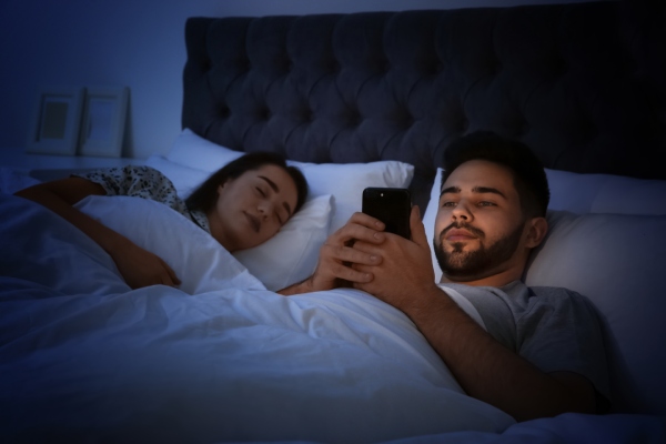 man using smartphone in bed at night